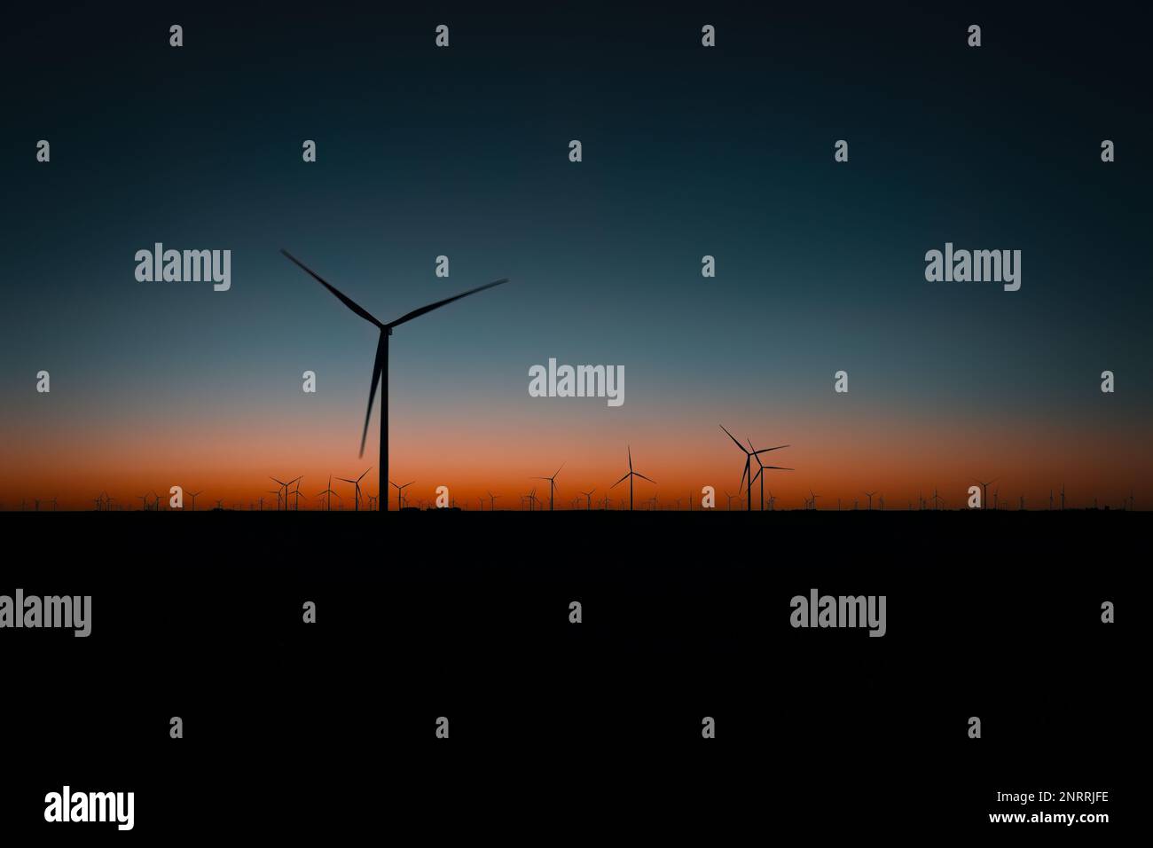 Die Morgensonne beginnt am Horizont hinter einer Windfarm in Minneola, Kansas, zu leuchten. Stockfoto