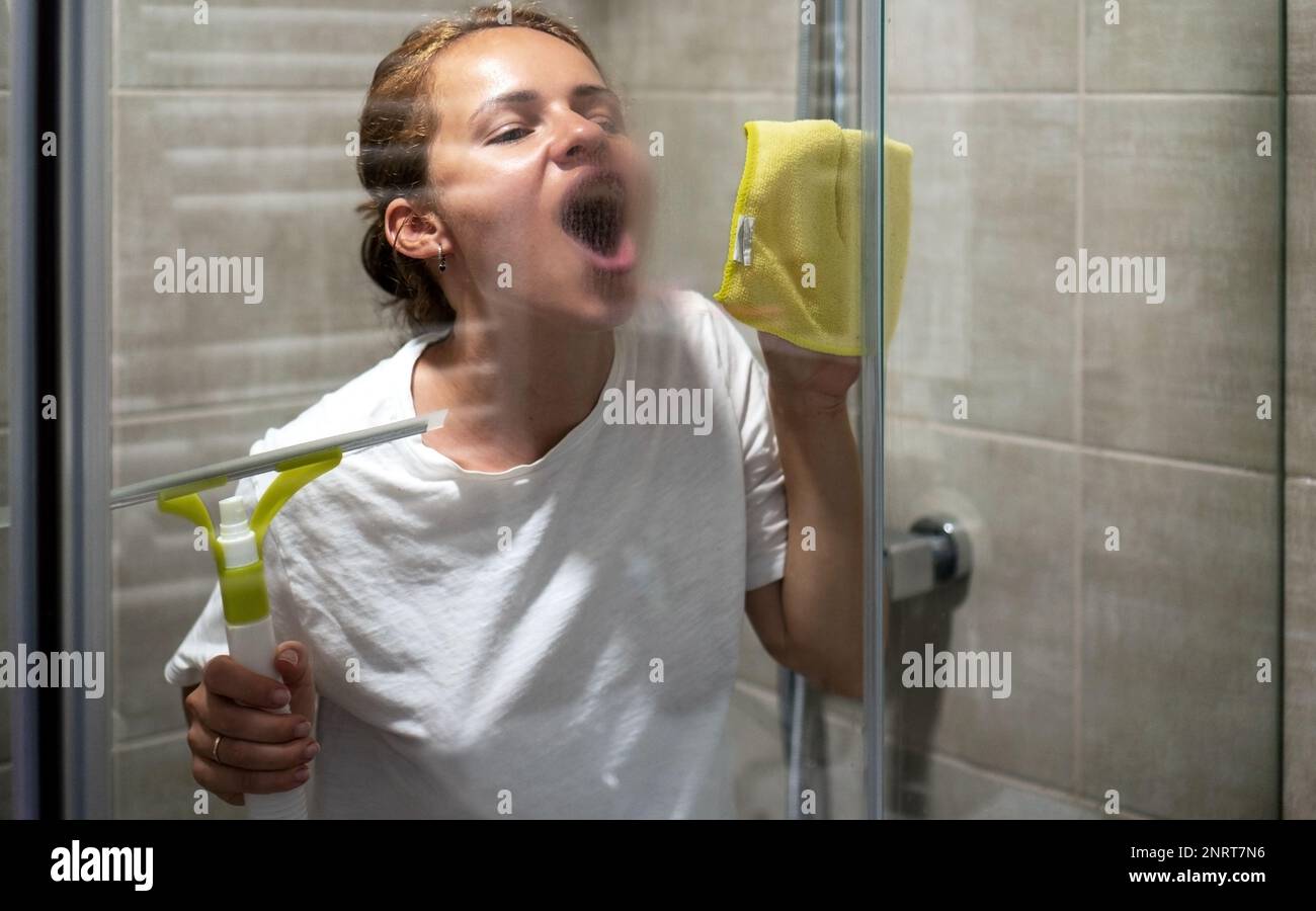 Frau atmete auf Glas, während sie die Glaswand im Duschraum reinigte. Stockfoto