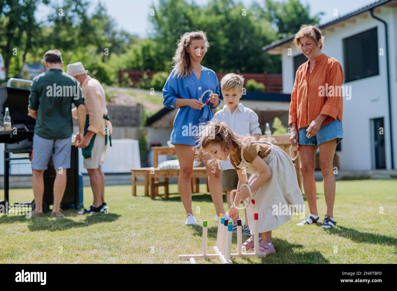 Mehrere Generationen Familienspiel Werfen Sie ein Ringspiel, wenn Sie im Sommer auf der Gartenparty draußen auf dem Hinterhof im Freien feiern. Stockfoto
