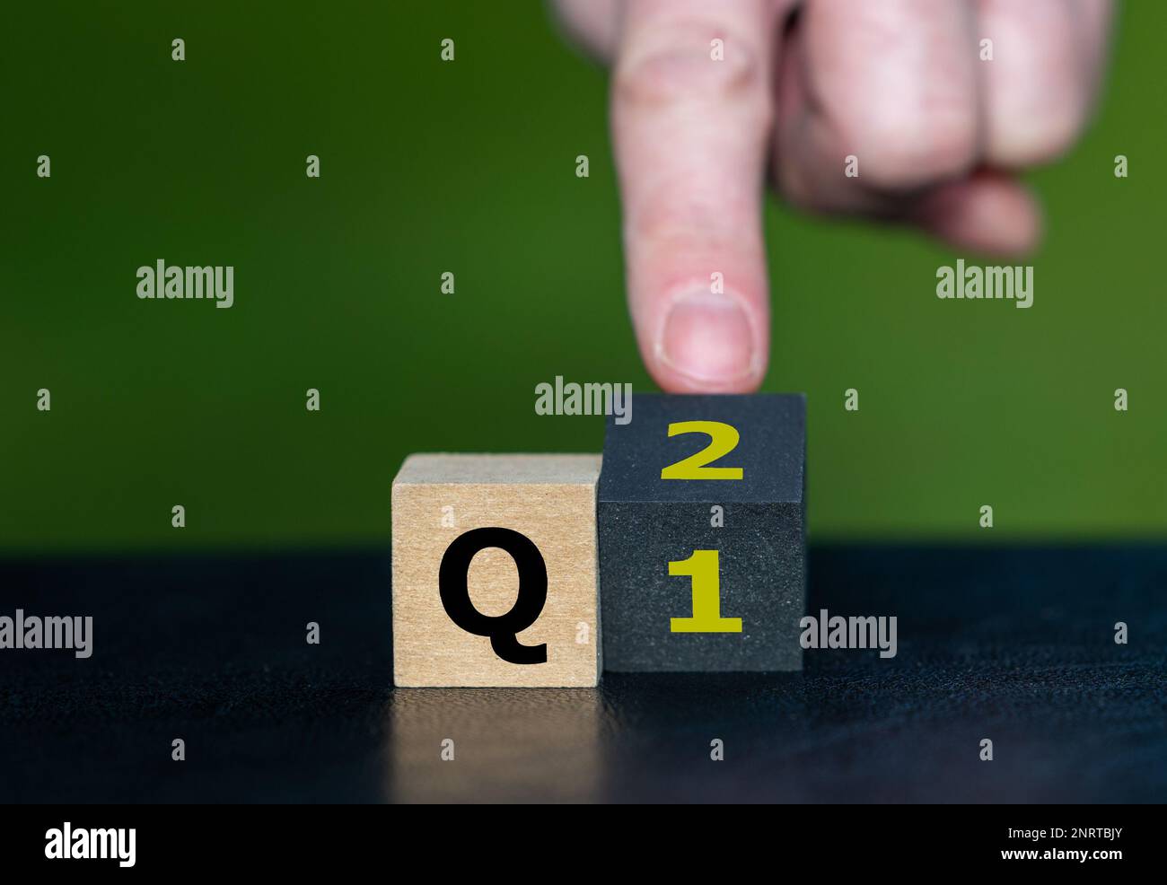Symbol für das 2. Quartal des Jahres. Die Hand dreht Würfel und ändert den Ausdruck Q1 in Q2. Stockfoto