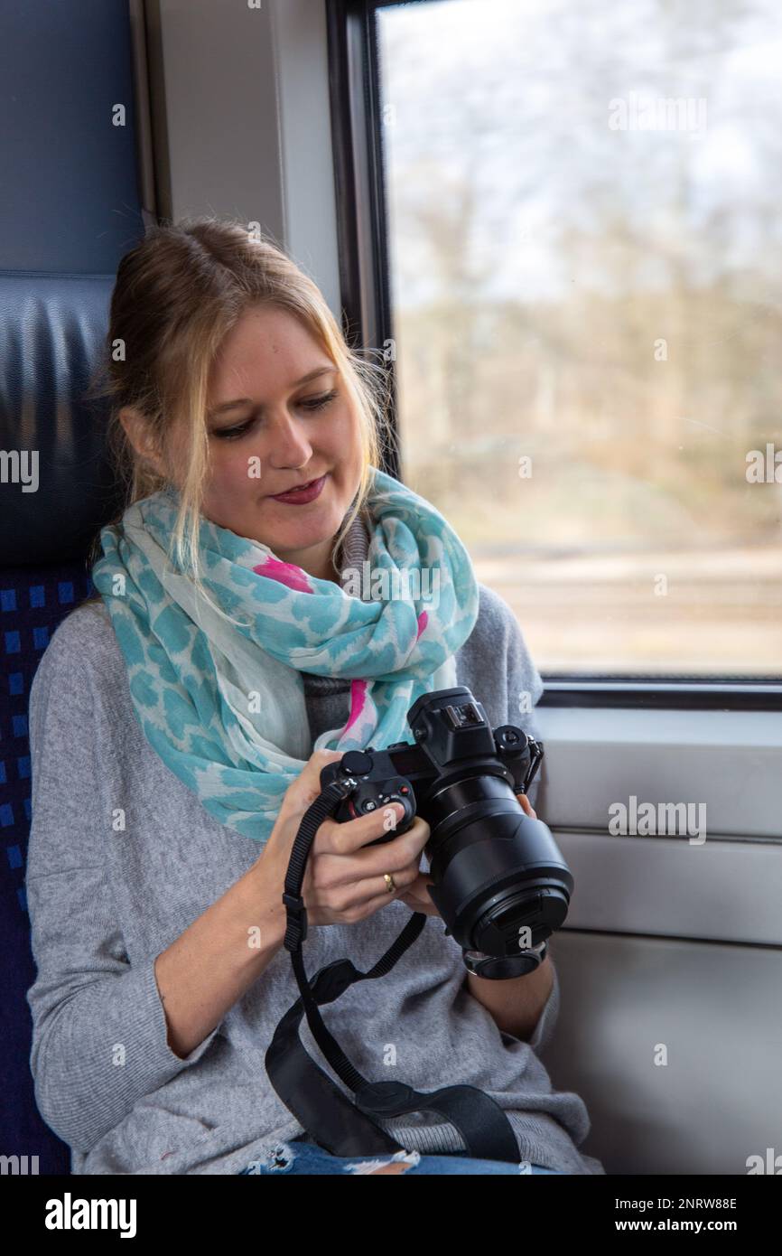 Junge Frau in einem Zug, die eine professionelle Kamerahand hält (Symbolbild) Stockfoto