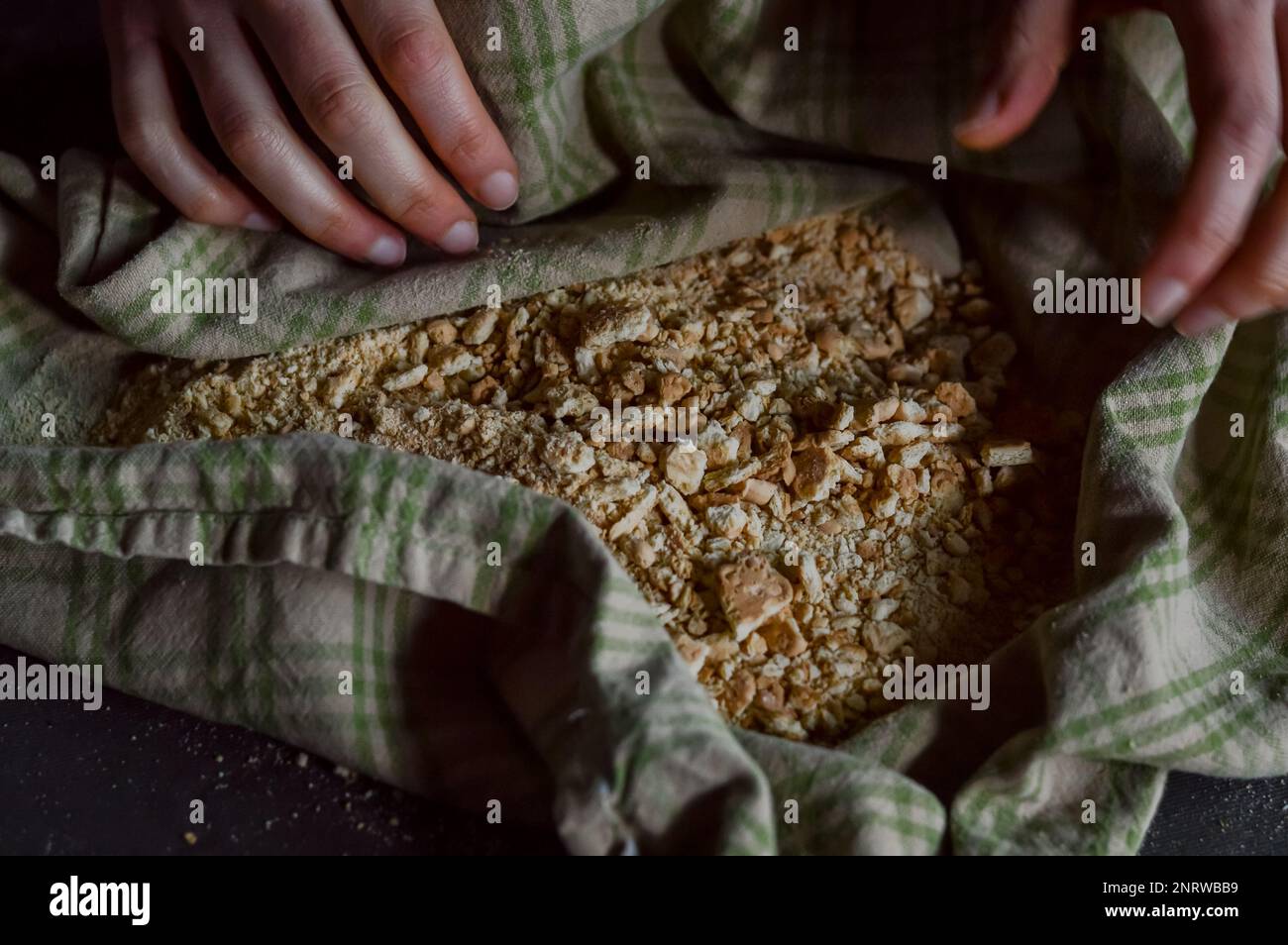 Kekskrümel in einem Küchenhandtuch, nachdem sie zerkleinert wurden, um die knusprige Basis eines Käsekuchen zu bilden Stockfoto