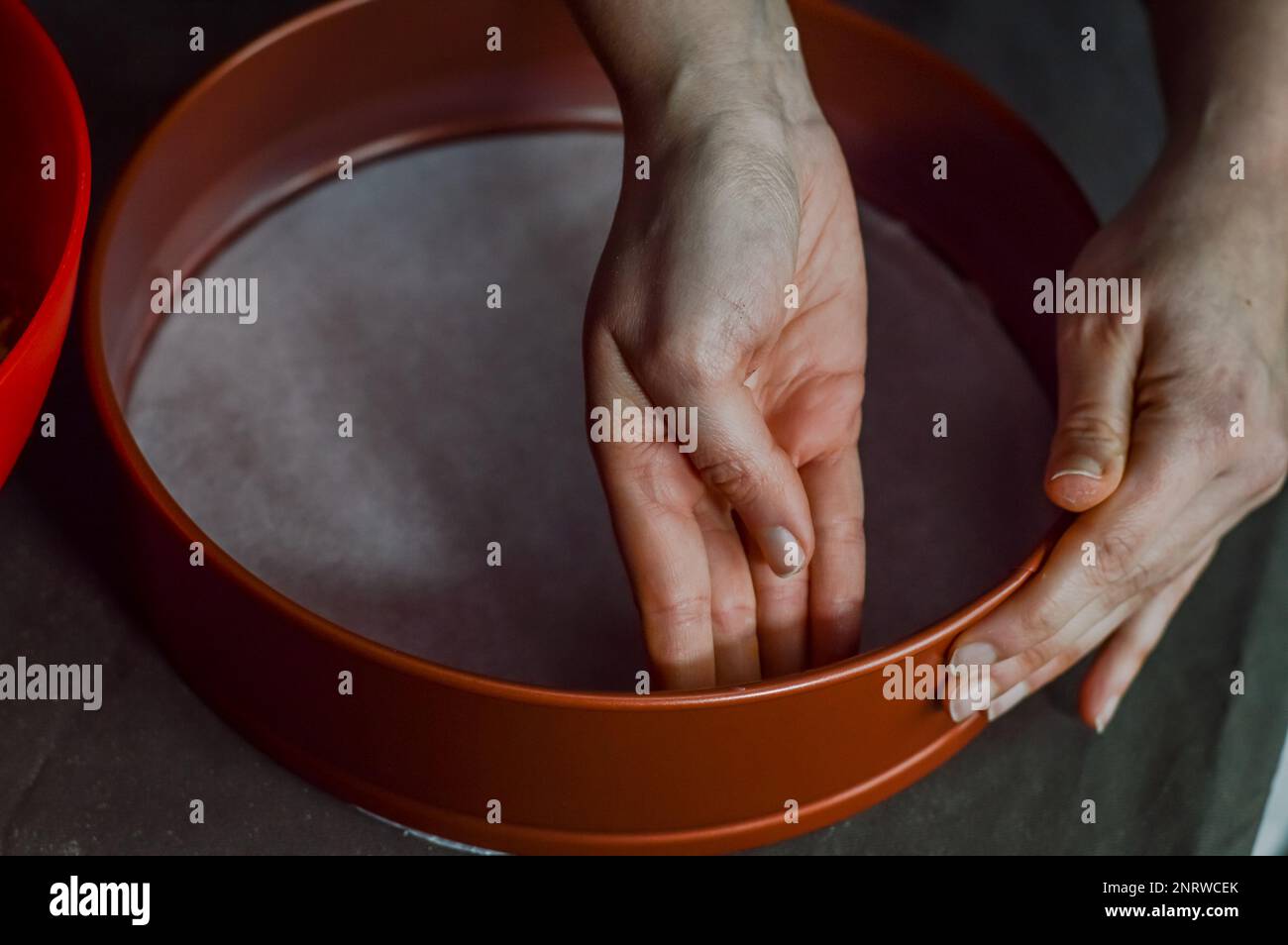 Die Hände buttern die Kanten der Pfanne, um die Krümelbasis zu backen und einen Käsekuchen zuzubereiten Stockfoto