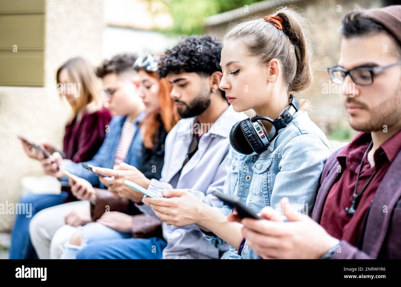 Seitenansicht von Milenial-Männern und -Frauen, die Smartphone-Geräte verwenden – Menschen, die von Mobiltelefonen abhängig sind – Tech-Life-Style-Konzept mit ständig vernetzten Teenagern Stockfoto