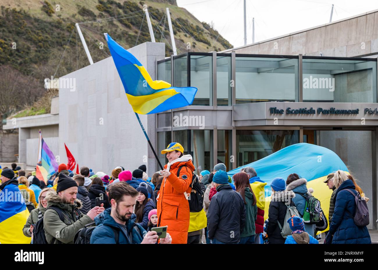 Menschen, die vor dem schottischen parlamentsgebäude zur Unterstützung der Ukraine zum Jahrestag der Invasion die ukrainische Flagge schwenken, Edinburgh, Schottland, Vereinigtes Königreich Stockfoto