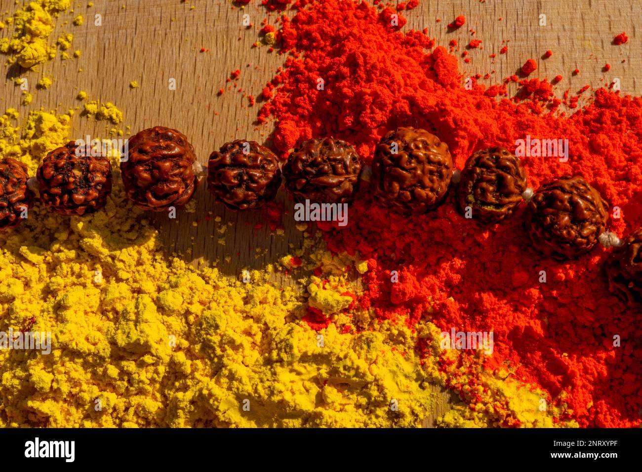 Farbenfrohes traditionelles holi-Pulver auf dem Tisch mit hölzernen Gebeten, indischen Perlen. Frohes holi. Konzept Indisches Farbfestival namens Holi. Organisches Gulal d Stockfoto