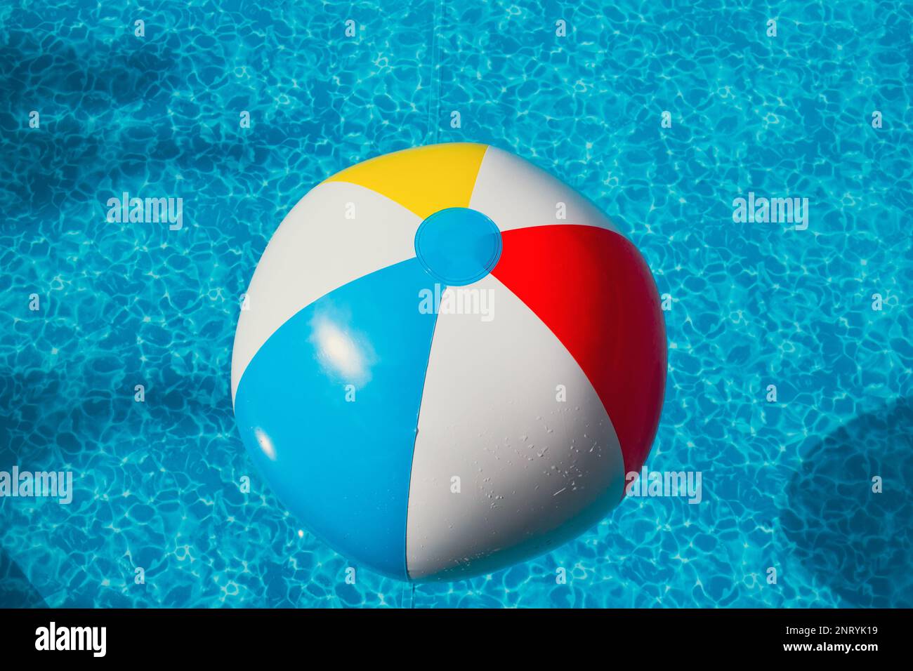 Aufblasbarer Strandball schwimmt in klarem blauem Wasser oder im Außenpool Stockfoto