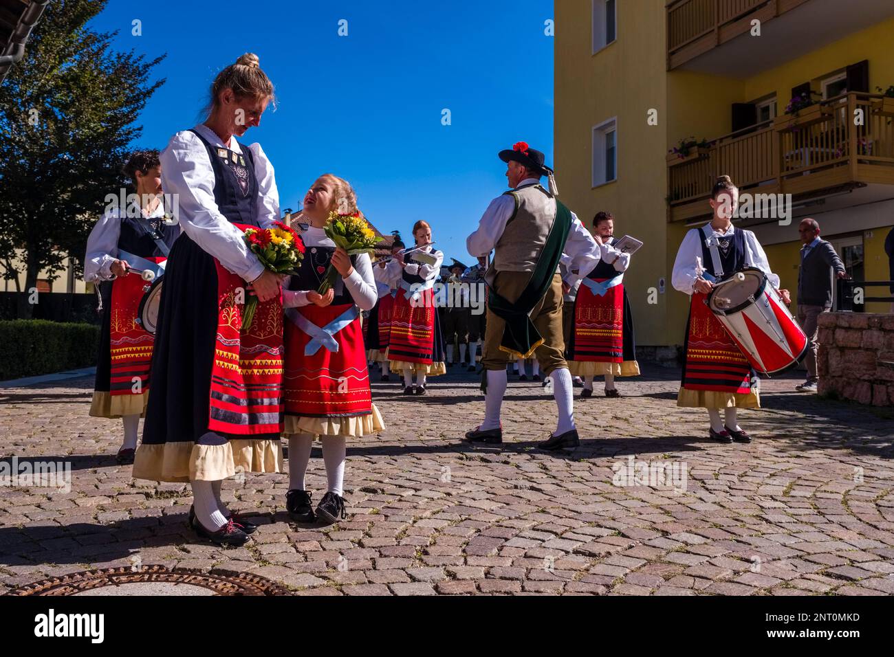 Traditionell gekleidete Leute spielen Musik während des Almabtriebs, dem Viehtrieb von der Bergweide, im Dorf Fai della Paganella. Stockfoto