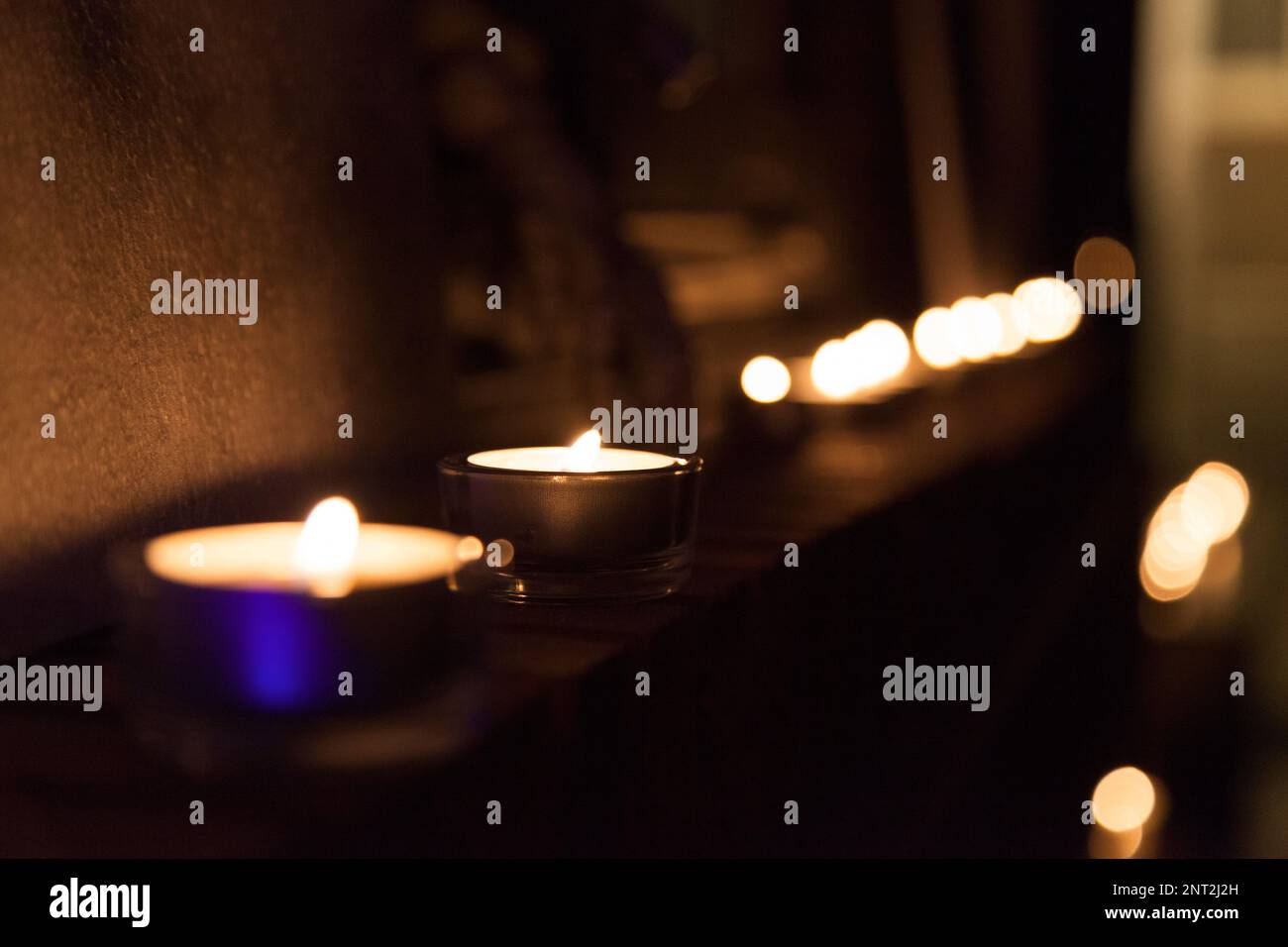 Photophores, die auf dem Kaminsims angeordnet sind und einen dunklen Raum beleuchten. Stockfoto