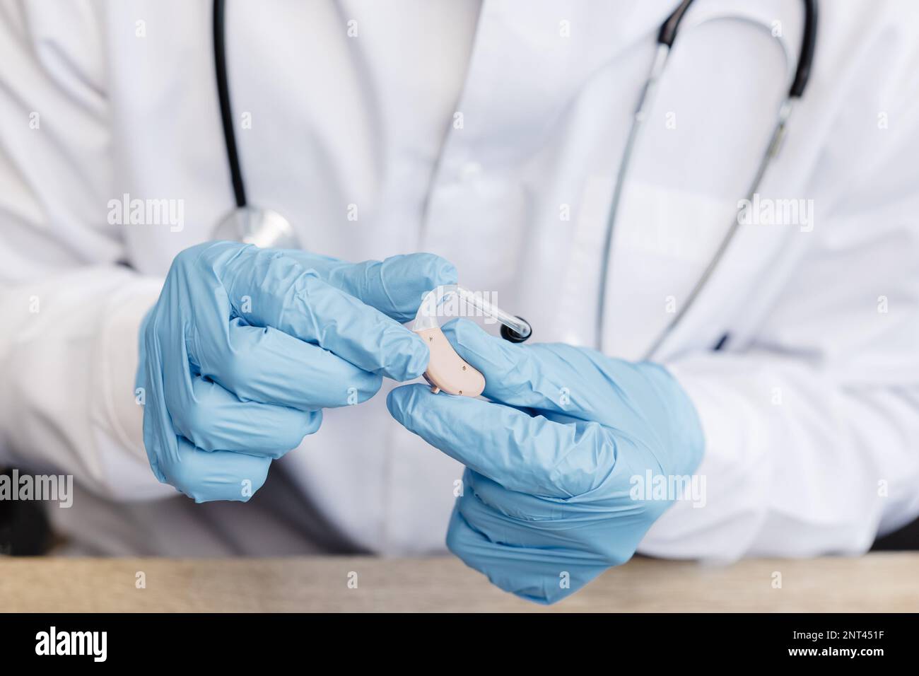 Ein HNO-Arzt hält ein Hörgerät in den Händen. Der Arzt konsultiert den Patienten. Stockfoto