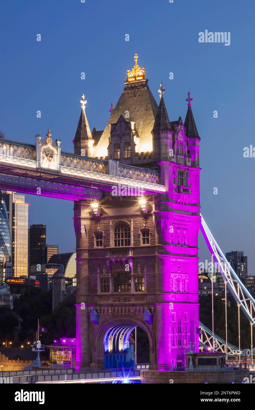 England, London, Tower Bridge mit violetter Beleuchtung und City of London Skyline Stockfoto