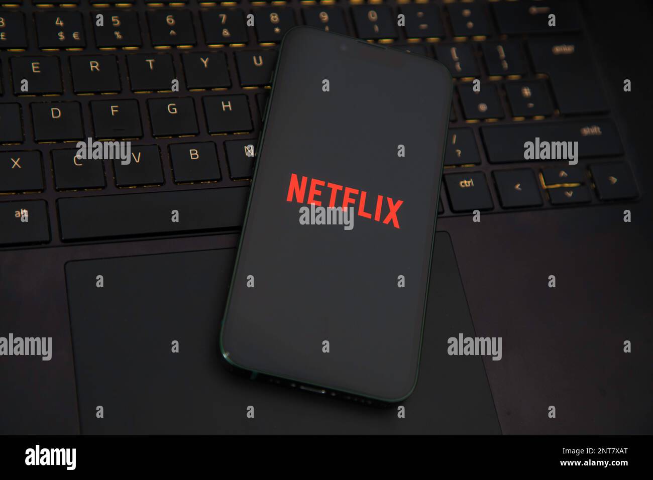 Die Netflix-App wird auf einem iPhone auf einem Laptop geladen Stockfoto