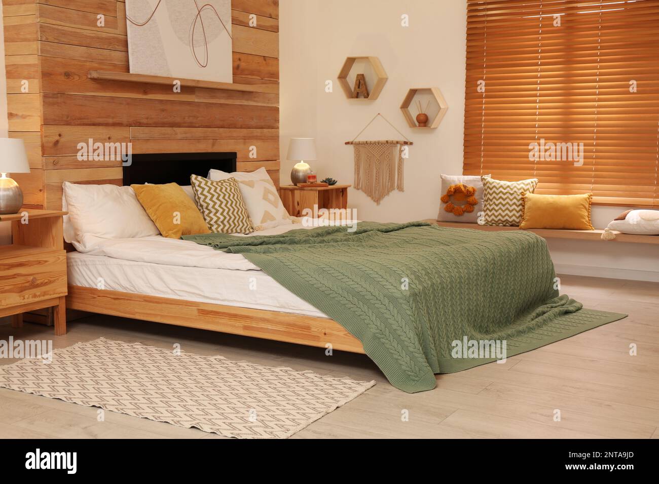 Stilvolle Innenausstattung mit großem, komfortablem Bett Stockfoto