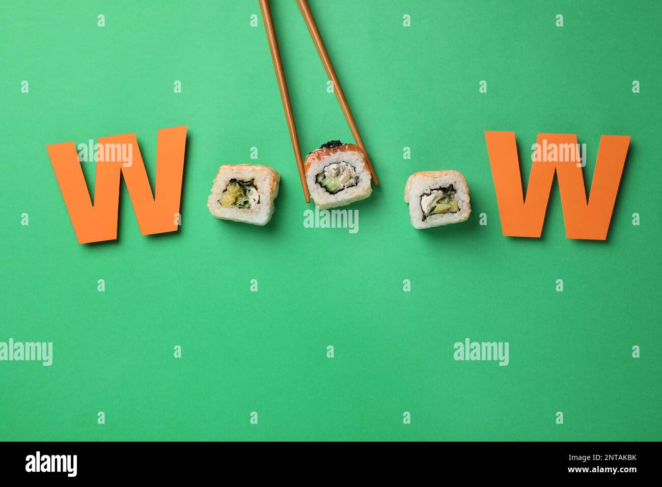 Word Wooow mit Sushi-Rollen und Papierbuchstaben auf grünem Hintergrund, flach liegend Stockfoto