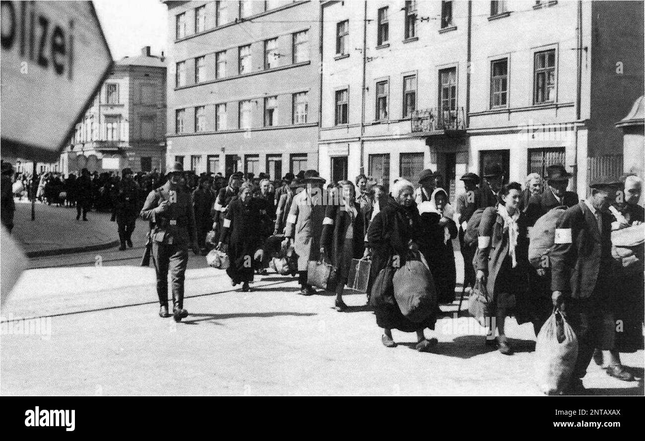 Deutsch besetzte Polen. Eine Kolonne von gefangenen Juden marschiert mit Bündeln entlang der Hauptverkehrsstraße in Krakau während der Liquidierung des Ghettos von Krakau. SS-Wachen überwachen die Deportation in die Vernichtungslager. Stockfoto