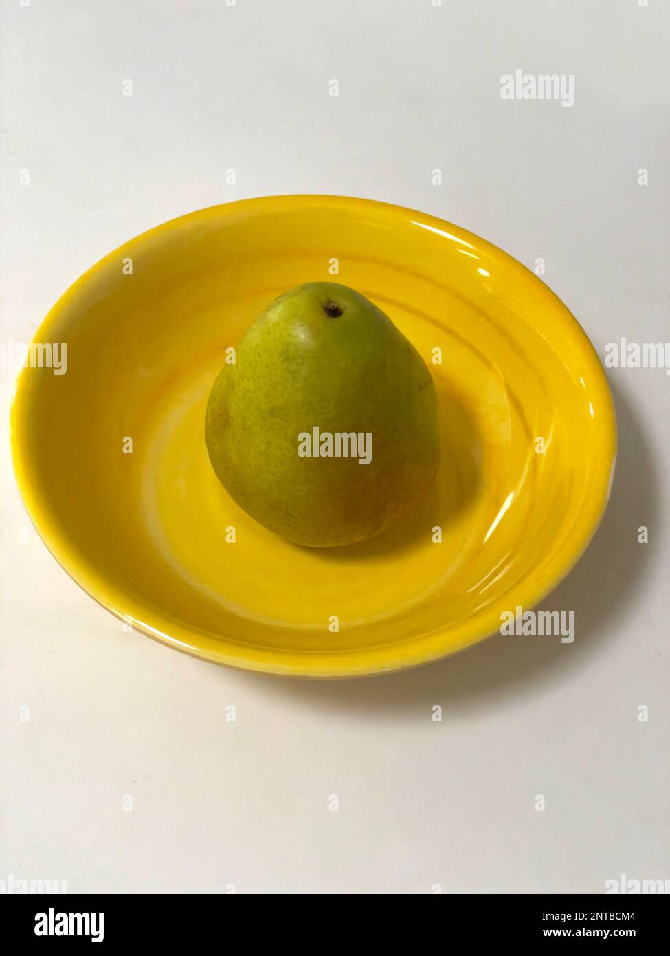 Eine grüne Birne auf einem gelben Teller. Stockfoto