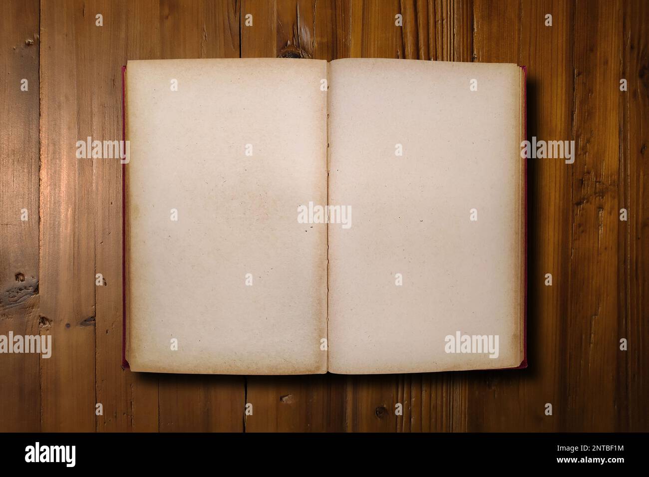 Nahaufnahme eines roten Buches geöffnet mit Kopierbereich auf einer braunen Holzplatte. Stockfoto