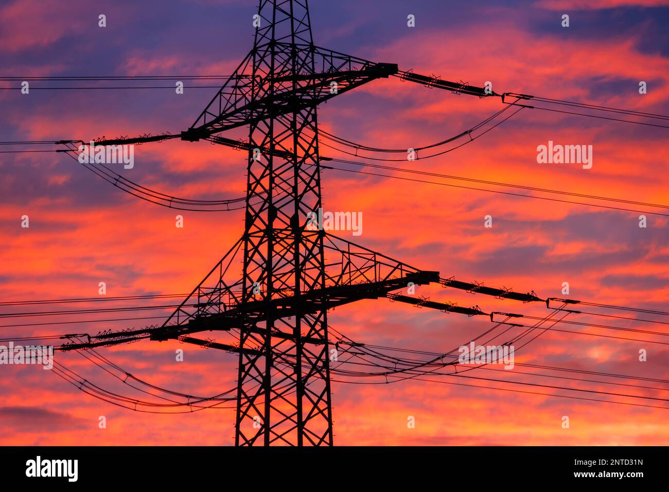 Hochspannungspylon gegen Sonnenuntergang Feuerroter Himmel Stockfoto