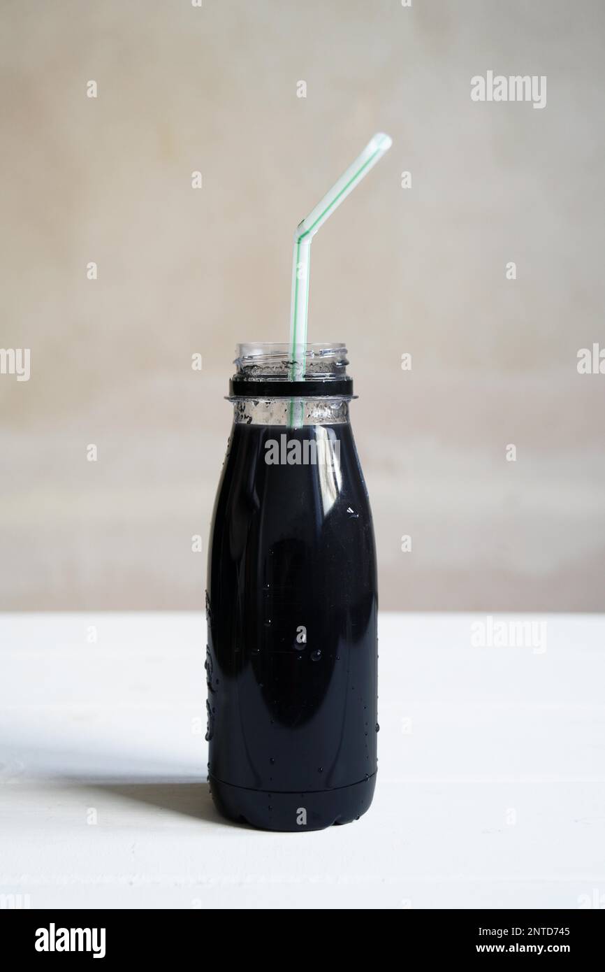 Schwarzer Smoothie Detox Drink mit Aktivkohle, Flasche mit Trinkhalm auf dem Tisch Stockfoto