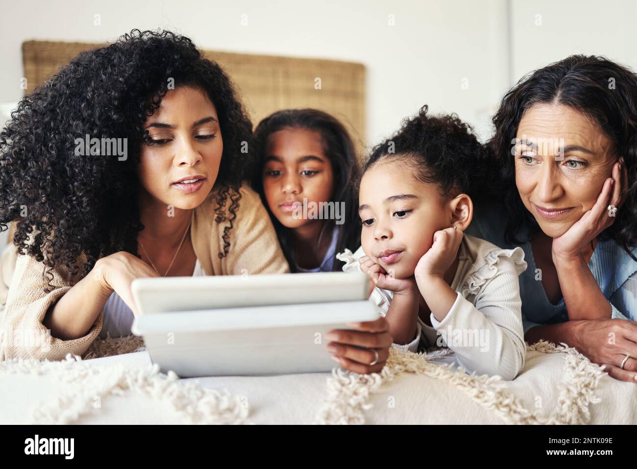 E-Learning-Tablet, Bildungsspiel für Kinder und Mutter mit Großmutter im Schlafzimmer. Familienhaus, Seniorin und Kinder in einer Wissensentwicklung Stockfoto