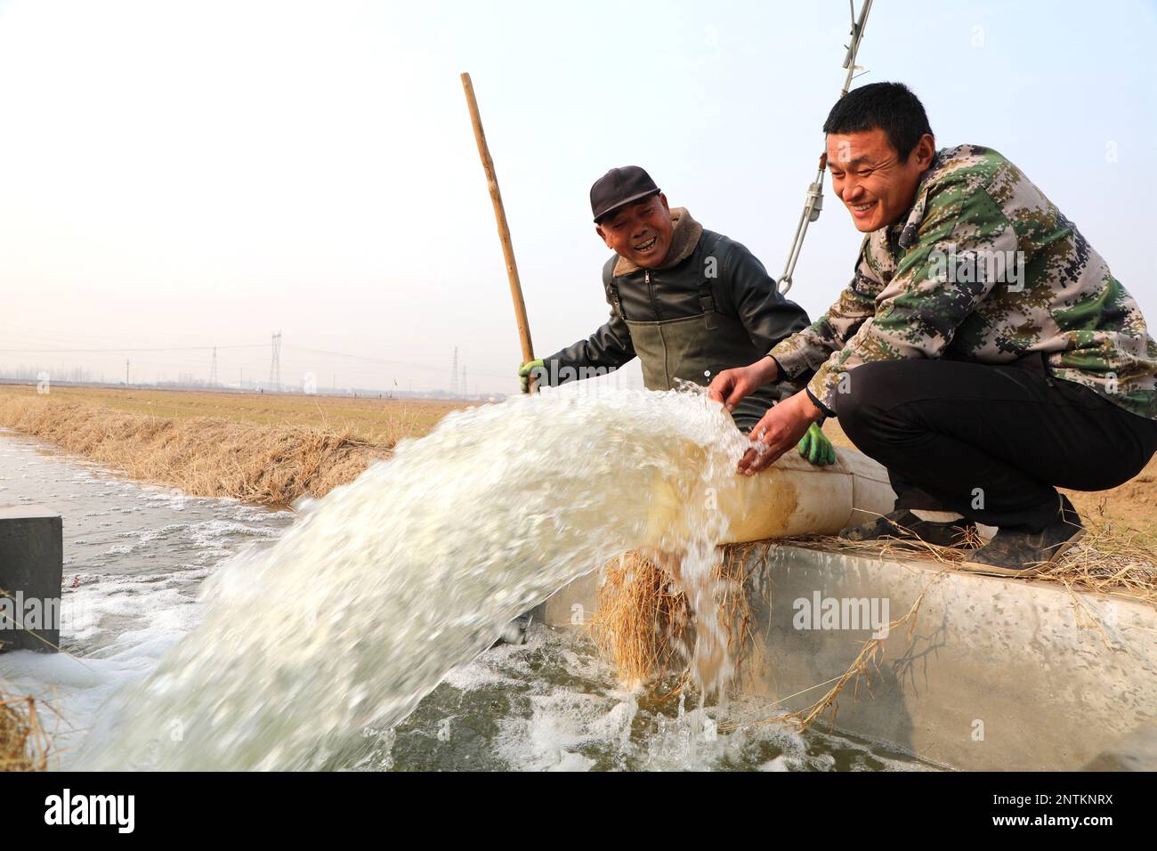 BINZHOU, CHINA - 28. FEBRUAR 2023 - zwei Bauern leiten Wasser zur Bewässerung eines Weizenfeldes in Huimin County, Binzhou Stadt, Shandong Provinz, China, Feb Stockfoto