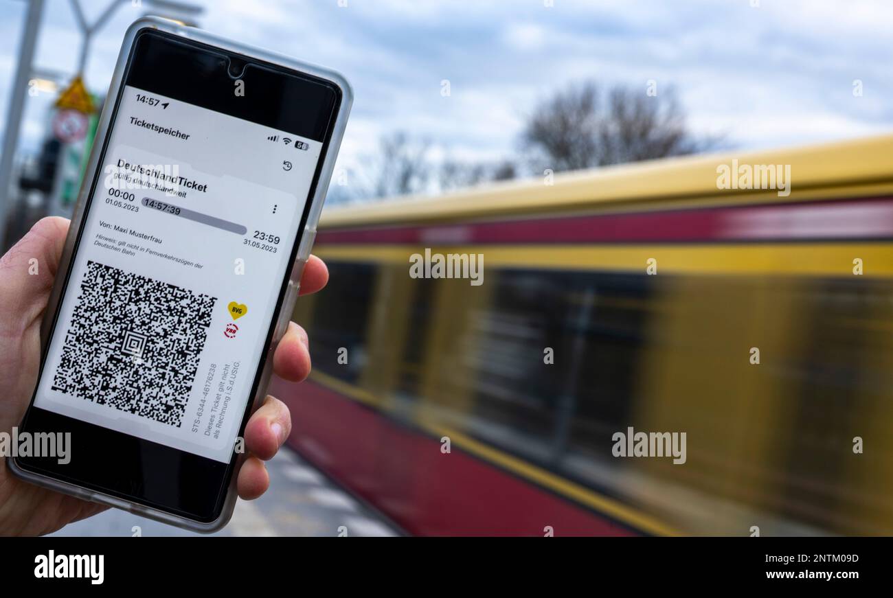 Berlin, Deutschland. 27. Februar 2023. Auf dem Display eines Smartphones wird der QR-Code des landesweiten Deutschland-Tickets neben den Logos von VBB und BVG angezeigt, während eine S-Bahn im Hintergrund vorbeifährt. Kredit: Monika Skolimowska/dpa/Alamy Live News Stockfoto