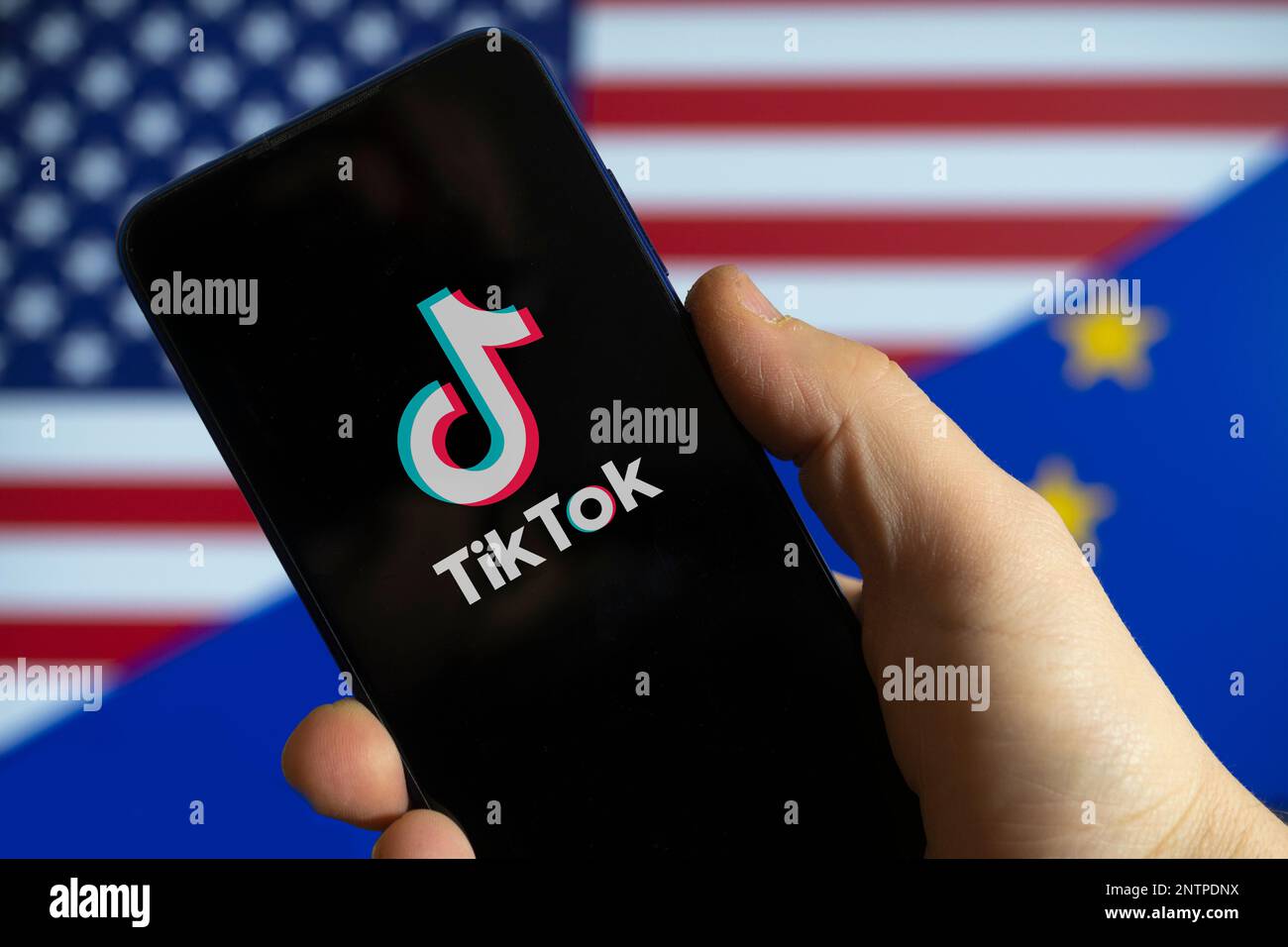 Carrara, Italien - 28. Februar 2023 - das TikTok-Logo mit der US- und der EU-Flagge im Hintergrund Stockfoto