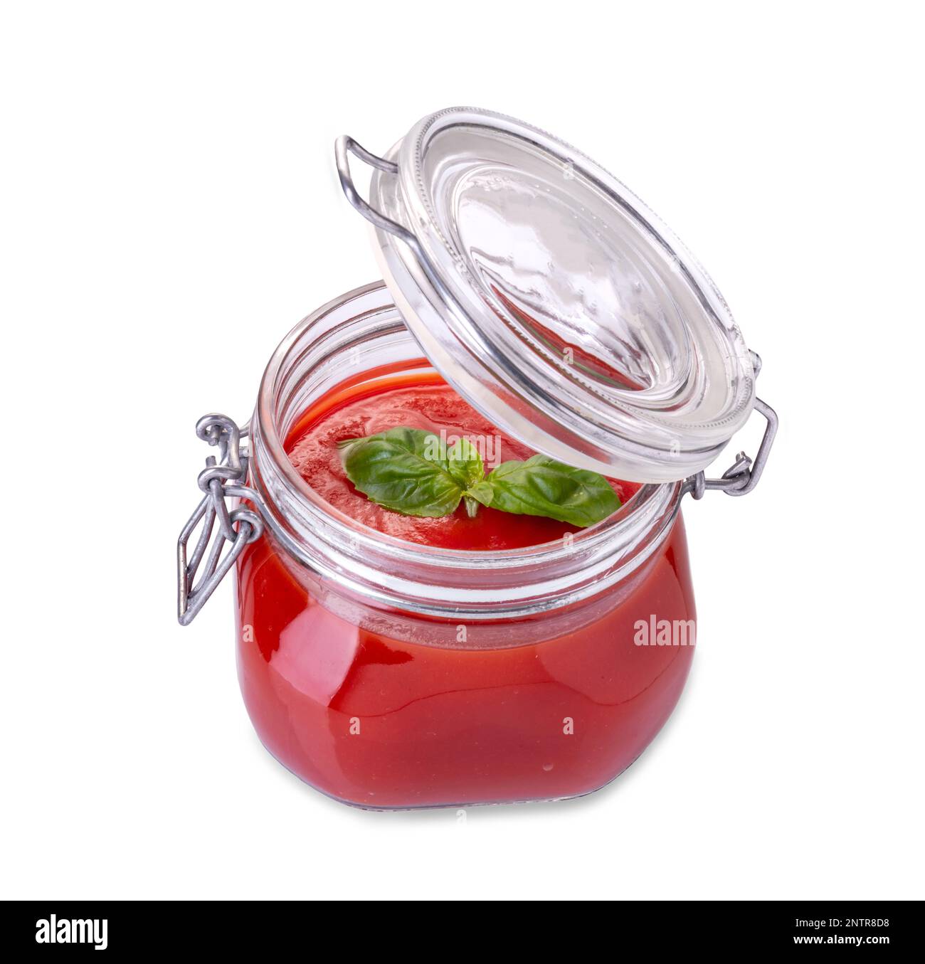Glasbehälter mit Tomatensoße, geöffnet mit Basilikumblättern im oberen Bereich isoliert auf weißem Hintergrund, Schnittpfad inbegriffen Stockfoto