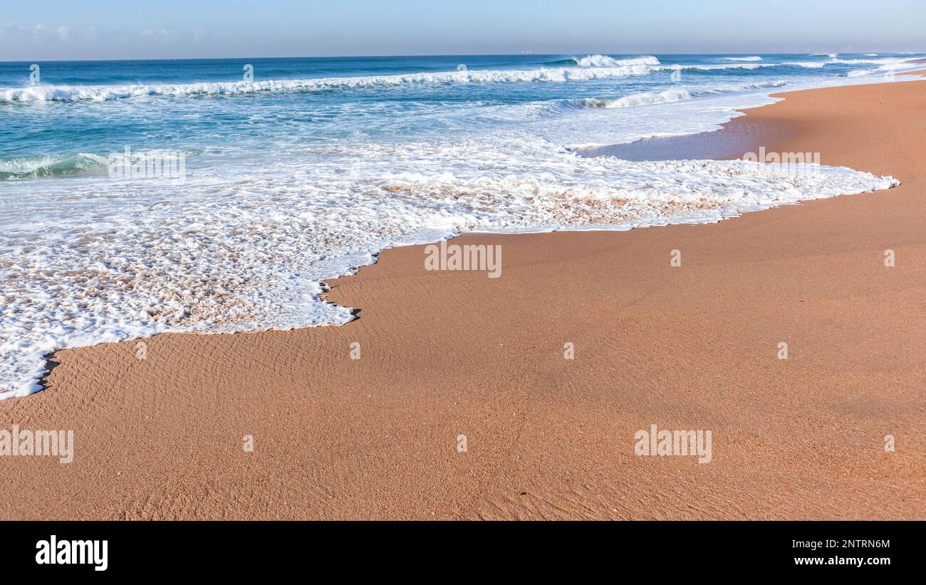 Strand blaue Ozeanwellen Himmel Nahaufnahme weiße Wasserschaumwelle entlang der Sandküste. Stockfoto