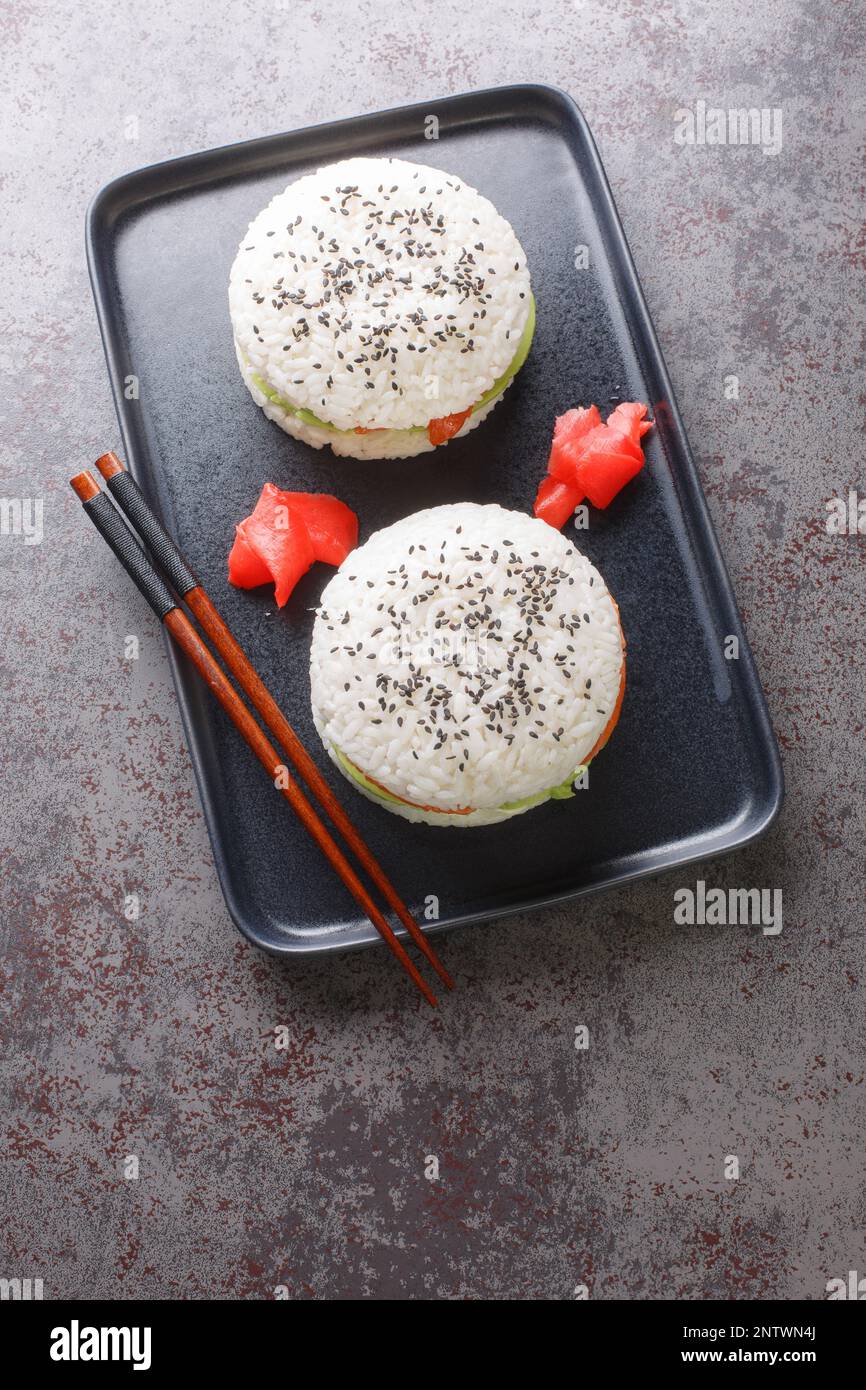Sushi-Burger mit Avocado und Lachs auf dunklem Hintergrund. Selektiver Fokus. Vertikale Draufsicht von oben Stockfoto