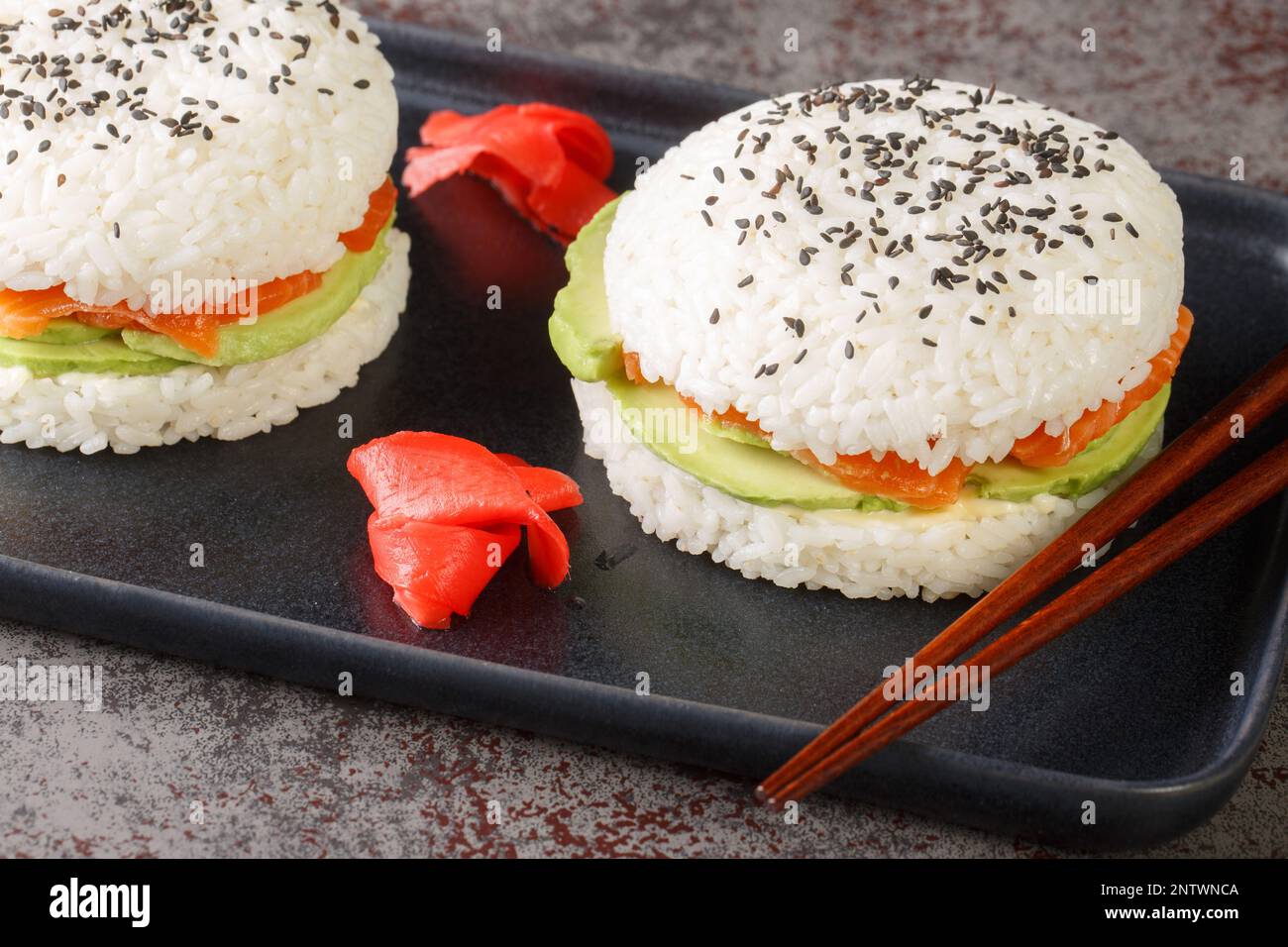 Japanisches Sushi-Sandwich mit Reis, Lachs, Avocado und Sesam aus nächster Nähe auf einem Teller auf dem Tisch. Horizontal Stockfoto