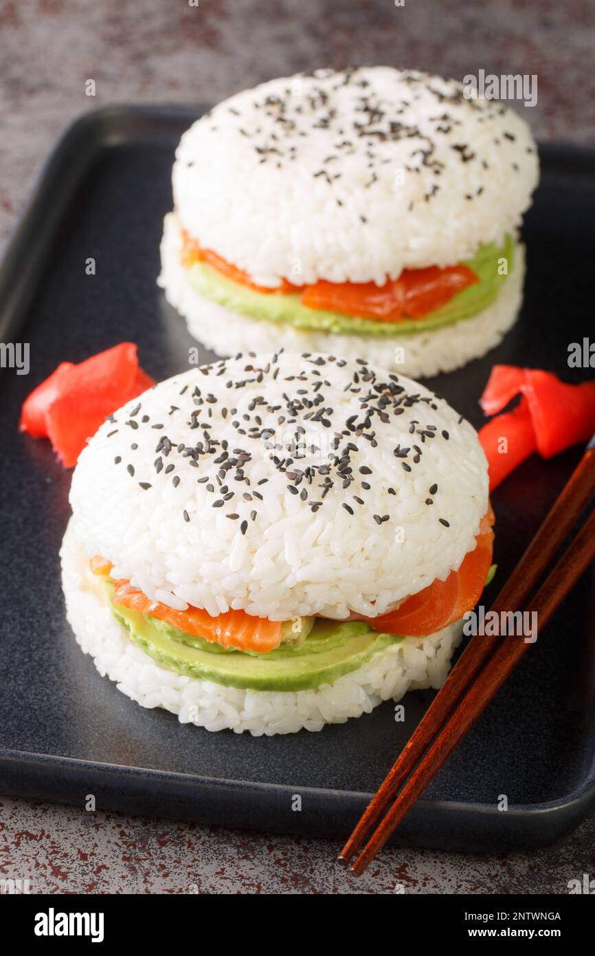 Sushi-Burger mit Avocado und Lachs auf dunklem Hintergrund. Selektiver Fokus. Vertikal Stockfoto