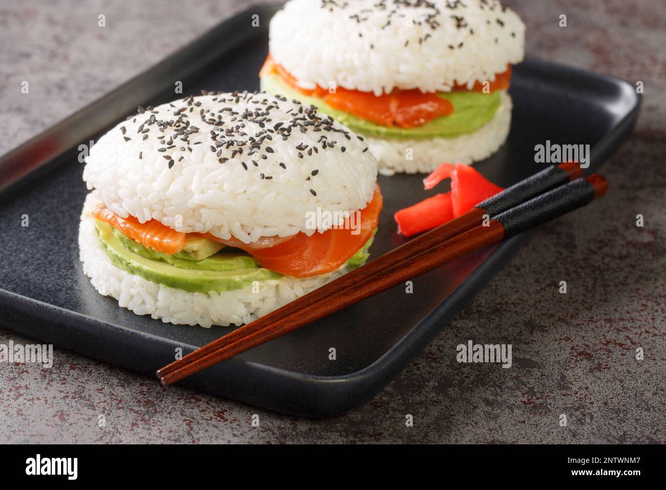 Sushi-Burger mit Lachs, Avocado und Reis aus nächster Nähe auf einem Teller auf dem Tisch. Horizontal Stockfoto