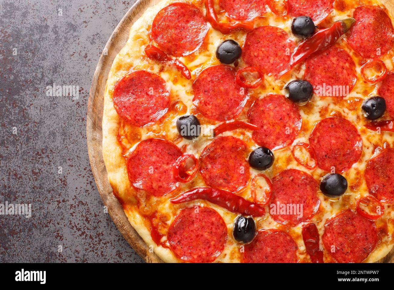 Italienische Pizza Diavola mit scharfer Salami und Chilischoten aus nächster Nähe auf einem Holzbrett auf dem Tisch. Horizontale Draufsicht von oben Stockfoto