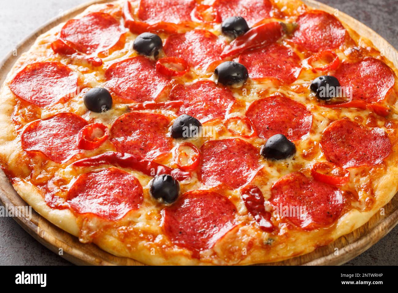 Italienische Pizza Diavola mit scharfer Salami und Chilischoten aus nächster Nähe auf einem Holzbrett auf dem Tisch. Horizontal Stockfoto