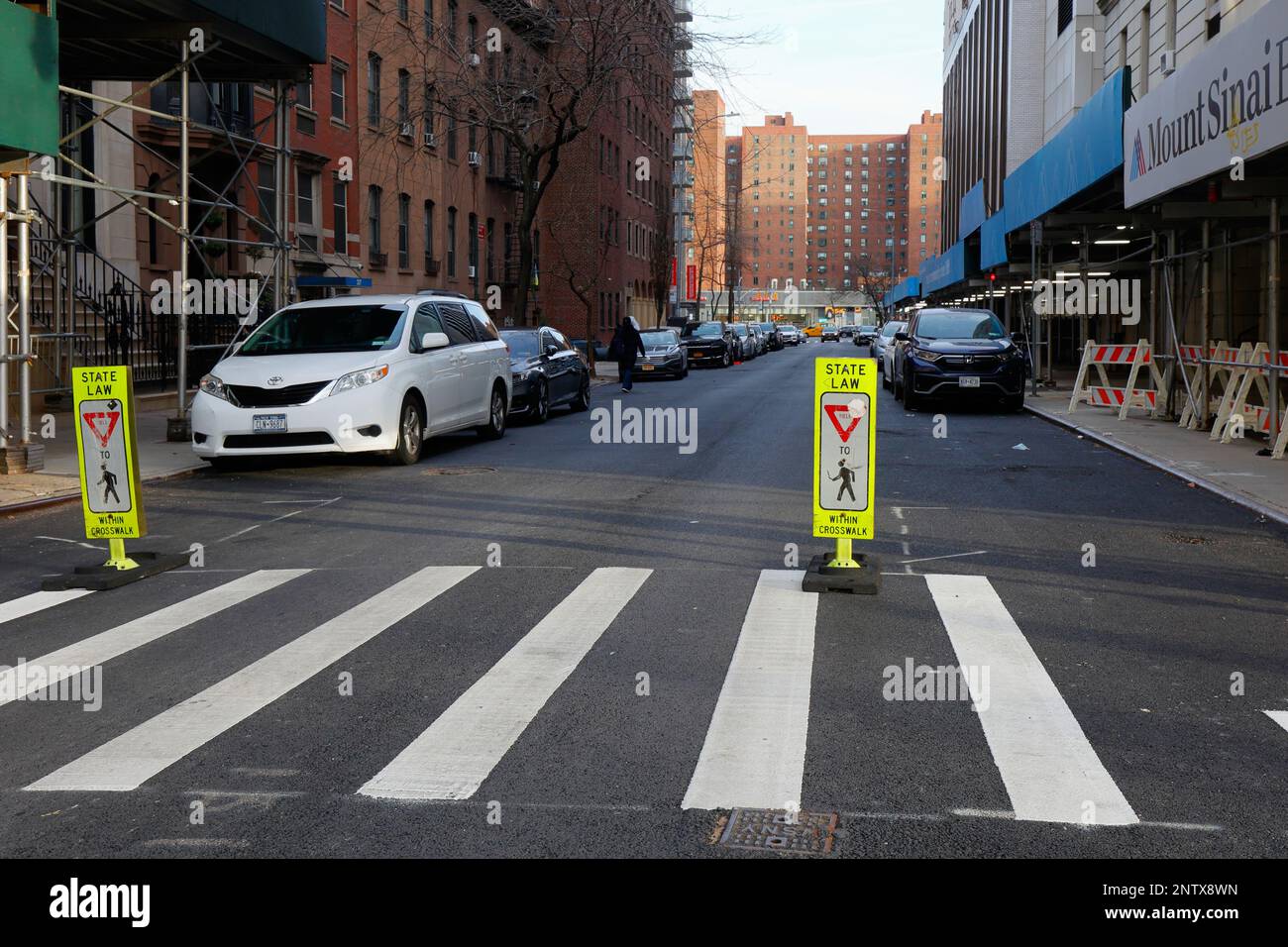Die seltene Beschilderung „State Law ergeben sich für Fußgänger innerhalb des Crosswalk“ an einem markierten Fußgängerübergang, aber ohne Stoppschilder, in Manhattan, New York City Stockfoto