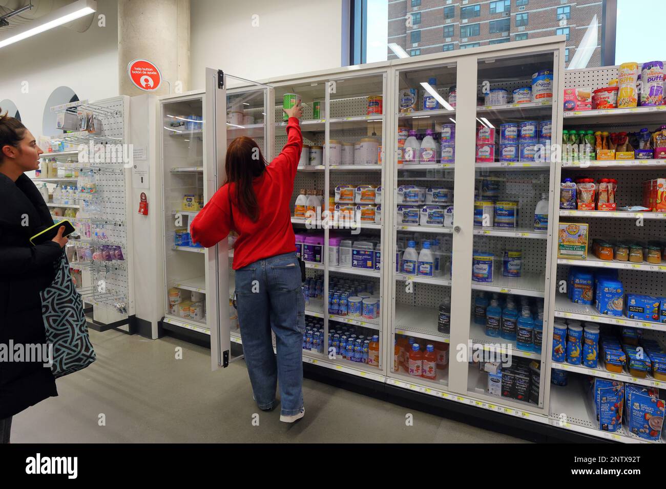 Ein Einzelhandelsmitarbeiter greift nach einer Dose Babymilch aus einem verschlossenen Schaukasten in einem Target Store in New York City, 14. Februar 2023. Stockfoto