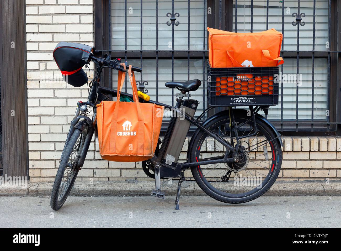 Ein E-Bike mit elektrischer Batterie und Grubhub-Thermalsäcken für Lebensmittellieferungen vor einem Gebäude in New York City. Stockfoto
