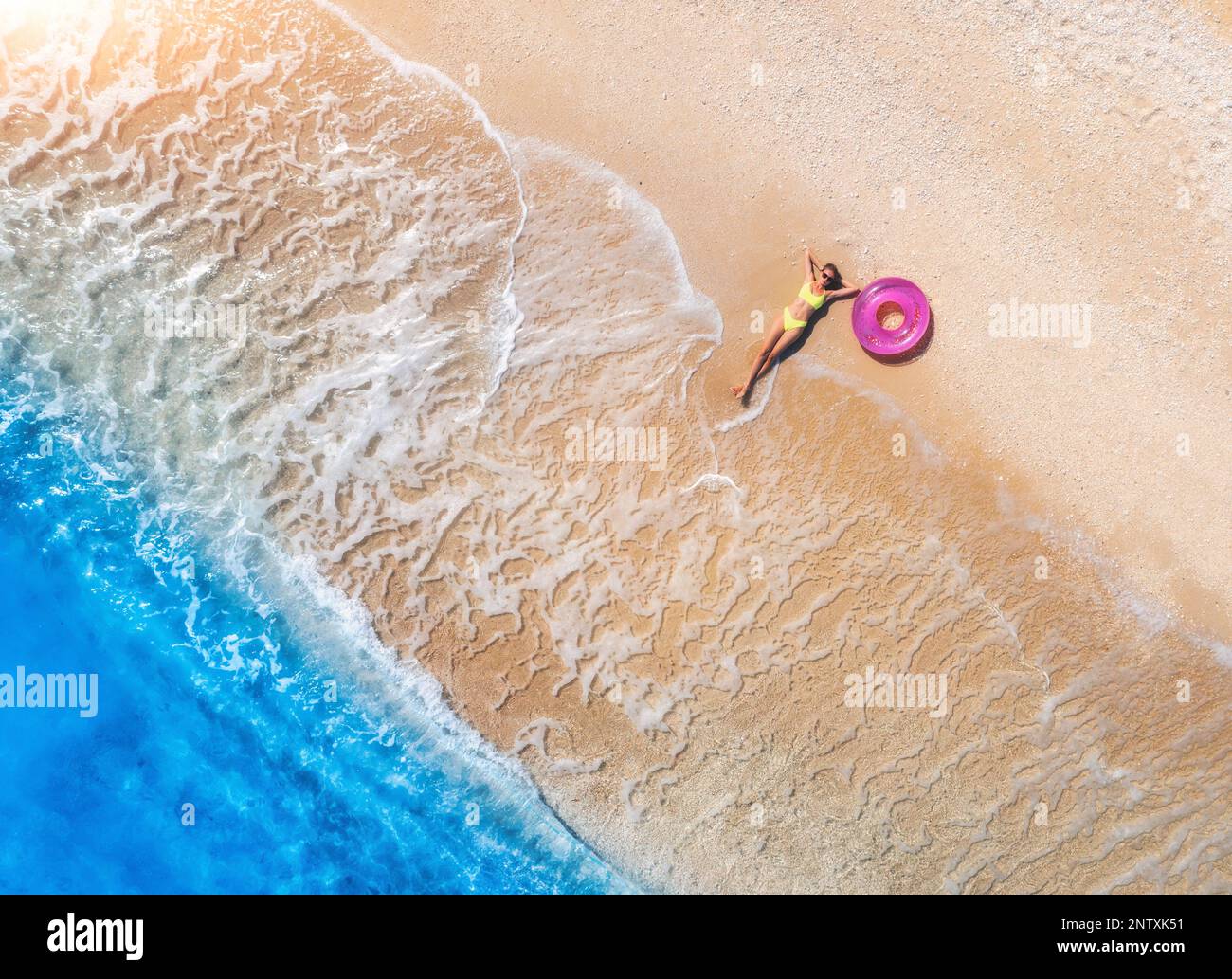 Luftaufnahme einer jungen Frau mit rosa Schwimmring am sandigen Strand Stockfoto