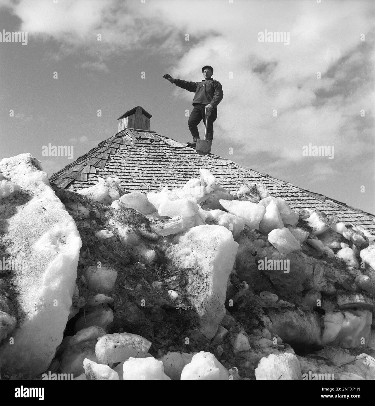 Naturkatastrophe in den 1940er Jahren. Im Frühsommer, den 20-23. Mai 1944, überflutete das Wasser im Fluss Torne älv aufgrund einer Eismasse, die das Wasser 3,5 Meter höher als normal dämpfte. Die Konsequenzen waren schwerwiegend. Auf dem umliegenden Gelände wurden Meter Eis zurückgelassen, als das Wasser ablief und die Bauernhäuser und die Felder zerstörte. Ein Mann auf dem Dach eines Bauernhauses, bedeckt mit Eismassen in der Nähe des Dorfes Korpikylä bei Skogskärr Kristoffersson, Ref. H115-6 Stockfoto
