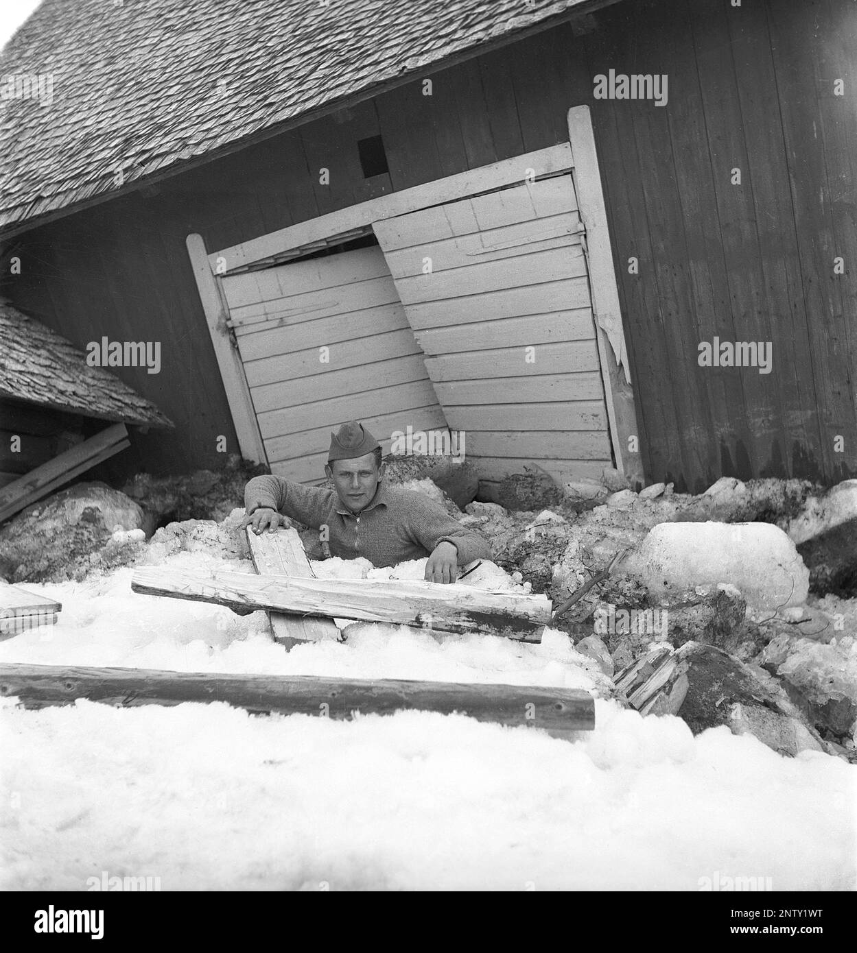 Naturkatastrophe in den 1940er Jahren. Im Frühsommer, den 20-23. Mai 1944, überflutete das Wasser im Fluss Torne älv aufgrund einer Eismasse, die das Wasser 3,5 Meter höher als normal dämpfte. Die Konsequenzen waren schwerwiegend. Auf dem umliegenden Gelände wurden Meter Eis zurückgelassen, als das Wasser ablief und die Bauernhäuser und die Felder zerstörte. Das Dorf Korpikylä in der Nähe von Skogskärr und ein Blick auf ein zerstörtes Bauernhaus und die Eisschlösser, die den Hof mit Trümmern bedecken. Ein Mann, der kaum über den Massen liegt. Kristoffersson Ref. H133-4 Stockfoto