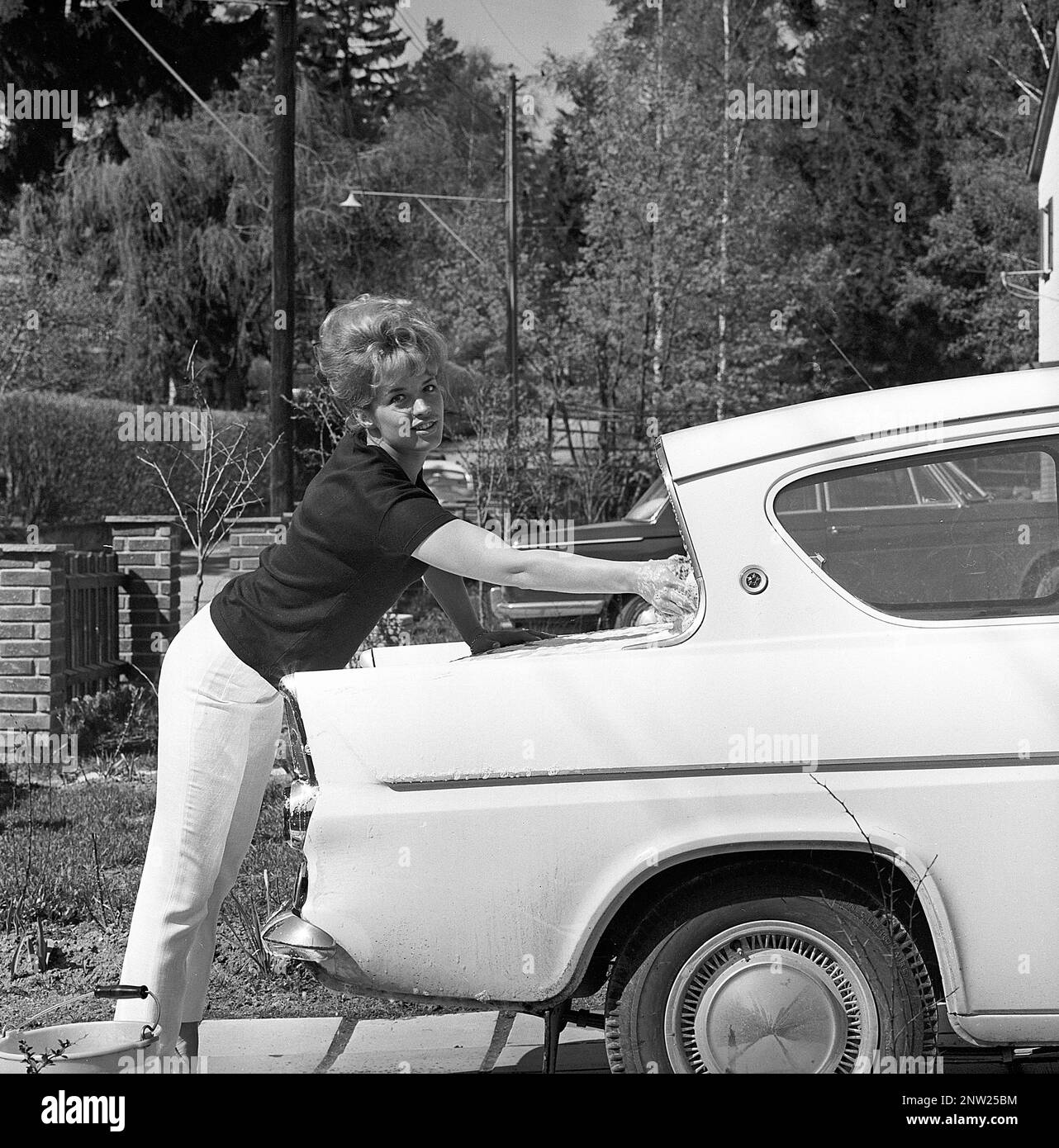 In den 1960er Jahren. Schauspielerin Lill-Babs wäscht ihr Auto, ein Ford Anglia. Ihre Mutter rechts. Schweden 1964 Stockfoto