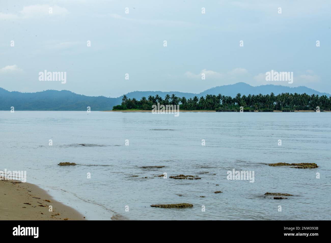 Das Foto bietet einen atemberaubenden Blick auf einen ruhigen Strand mit kristallklarem Wasser und sanften Wellen, die am Ufer schlagen. Stockfoto