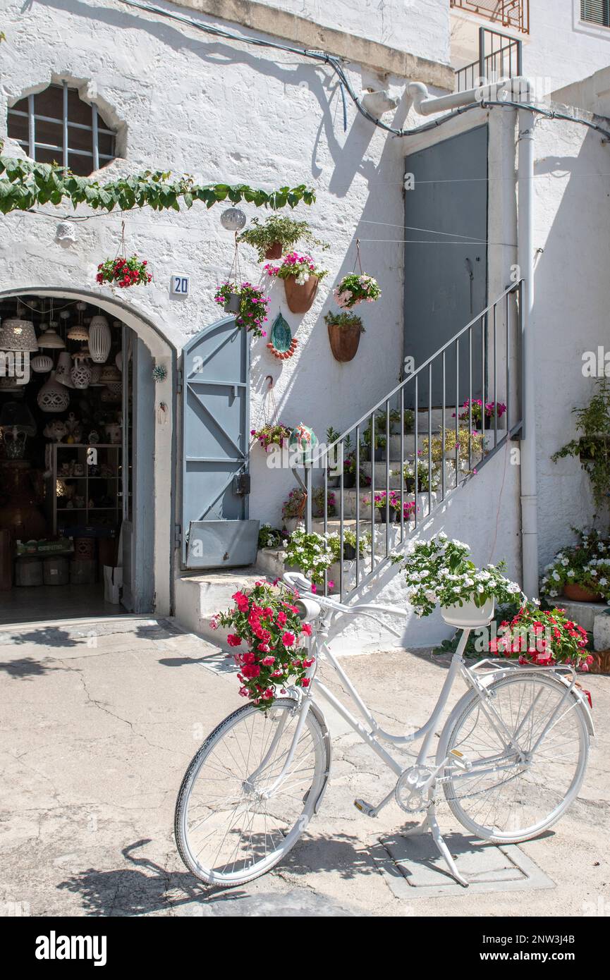 Ein weißes Fahrrad mit Blumen vor einer Keramikwerkstatt in Grottaglie, Apulien, Italien Stockfoto