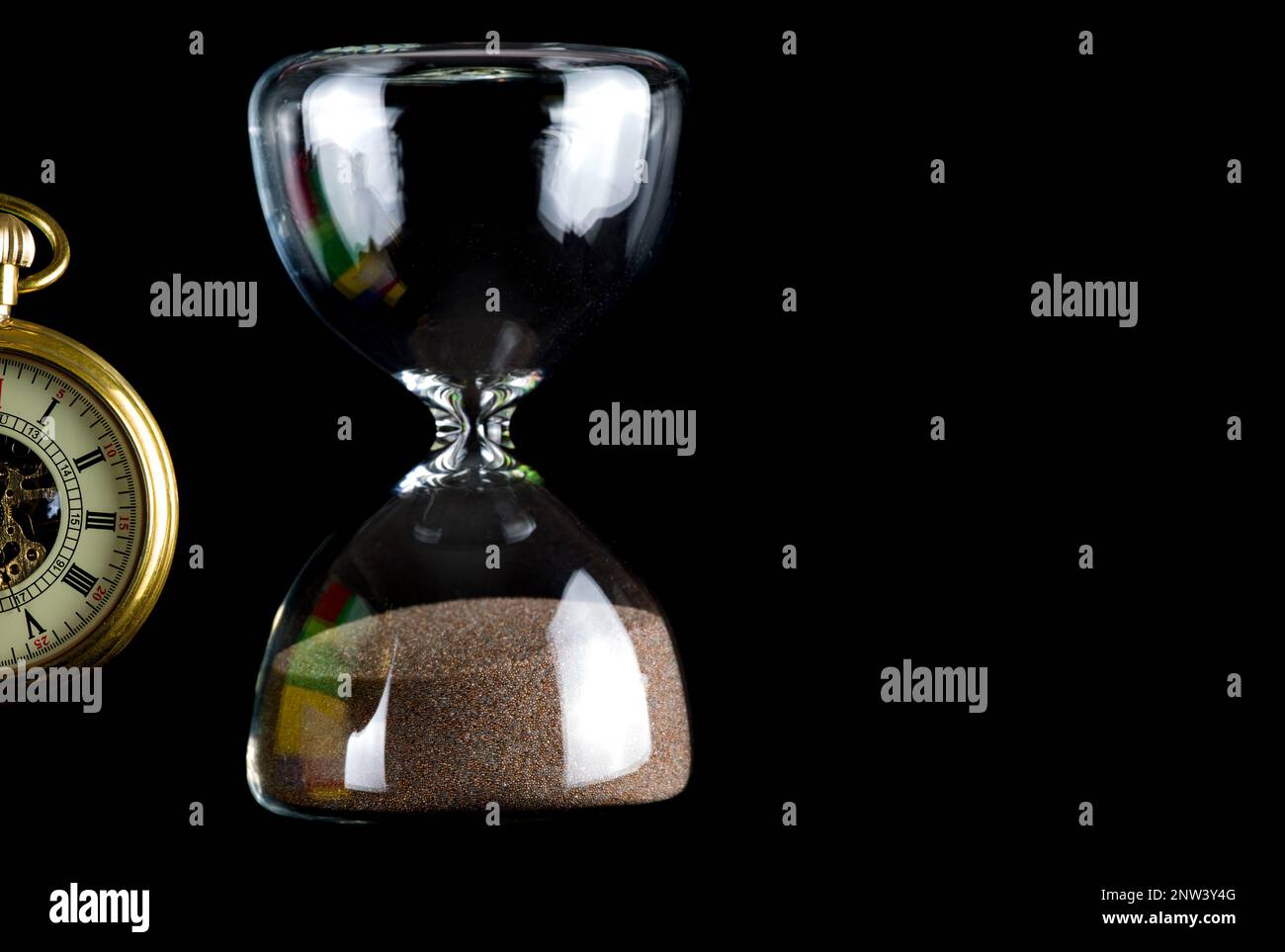 Teilansicht einer Taschenuhr mit vor schwarzem Hintergrund isolierter Sanduhr Stockfoto