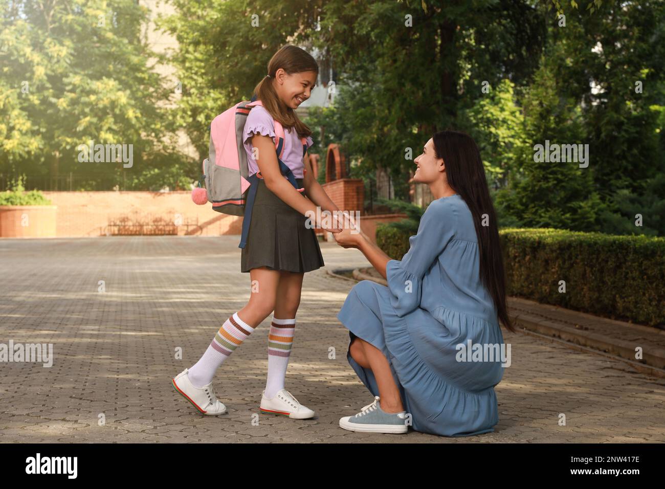 Mutter verabschiedet sich von ihrer Tochter vor der Schule im Freien Stockfoto