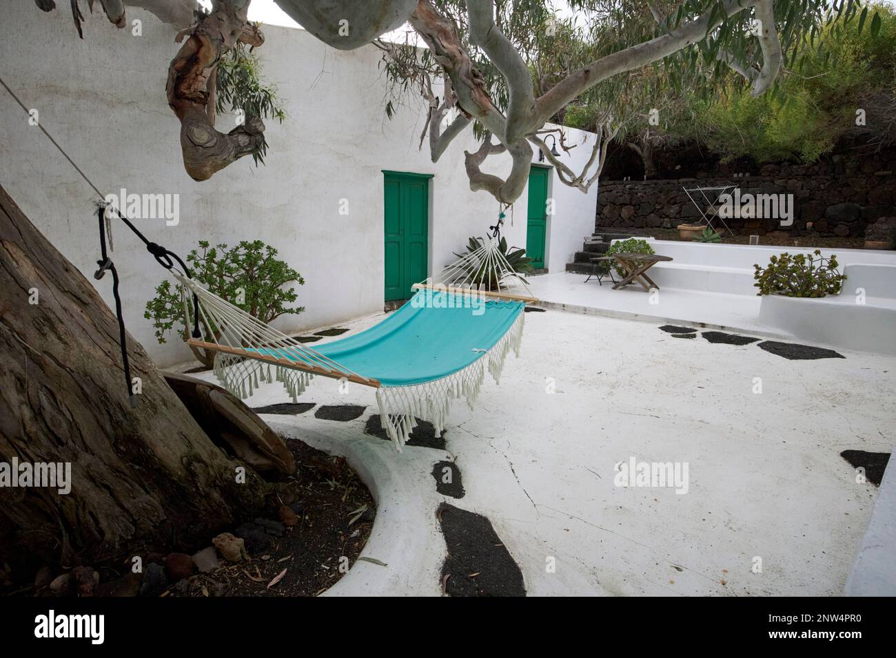 Hängematte, die von einem großen Eukalyptusbaum im Innenhof des traditionellen Finca-Bauernhauses hängt, weiß getünchte historische Wohnstätte in Lanzarote, Kanarische Inseln Stockfoto
