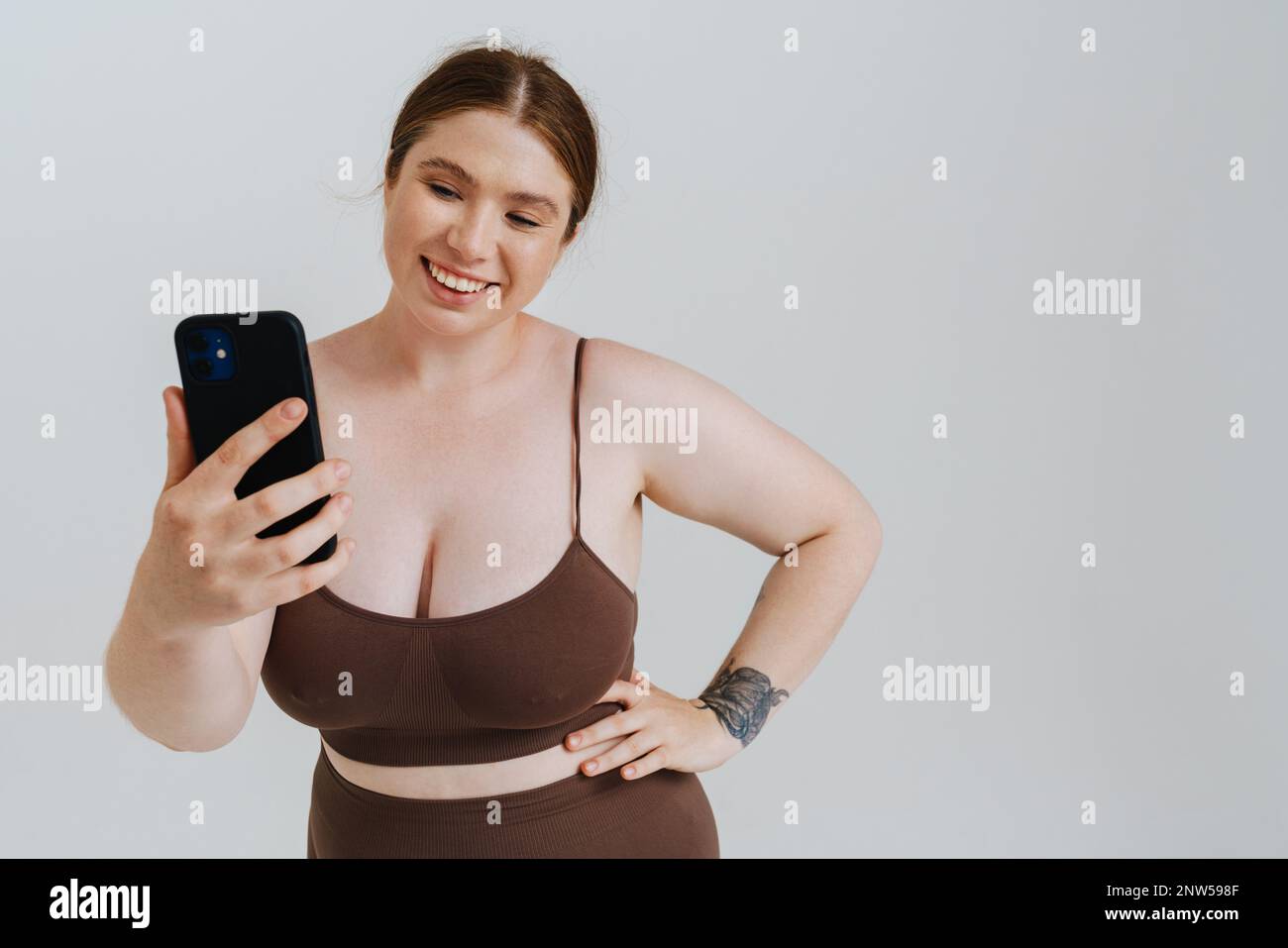 Eine europäische Frau lächelt, während sie ein Selfie-Foto auf dem Mobiltelefon macht, isoliert auf weißem Hintergrund Stockfoto