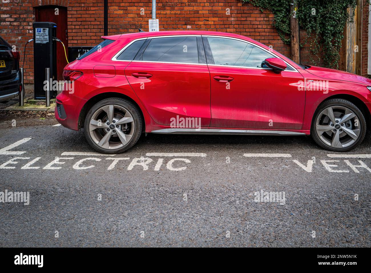 Elektrofahrzeug (EV) wird an einer Ladestation in einer Vorstadtstraße in Cardiff, Wales, Großbritannien, aufgeladen. Elektrifizierung des Verkehrs. Konzept. Stockfoto
