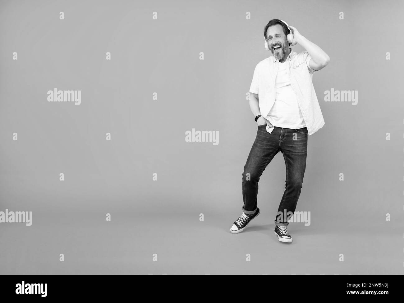 Bewegen Sie sich mit der Musik. Fröhlicher alter Mann singt zum Lied mit. Musik hören. Senioren tragen Stereokopfhörer. Viel Spaß beim Singen. Verjüngende Freude, Kopierbereich. Stockfoto